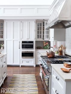 a kitchen with white cabinets and stainless steel stove top oven in the center, along with an area rug on the floor