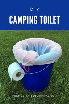 a blue trash can sitting on top of a lush green field next to a roll of toilet paper