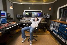 a man is sitting in front of some sound mixing equipment and his arms are behind him