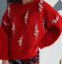 a woman wearing a red sweater and sequins