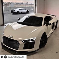 two white cars parked in a garage next to each other