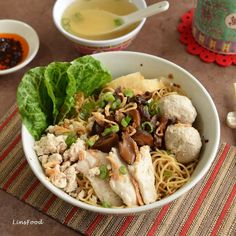 a bowl filled with noodles, meat and veggies next to chopsticks