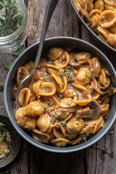 two pans filled with pasta and mushrooms on top of a wooden table