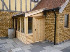 a small wooden building sitting on top of a stone floor next to a brick wall