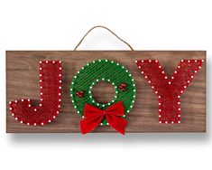 a wooden sign that says joy with a christmas wreath and bow hanging from the front