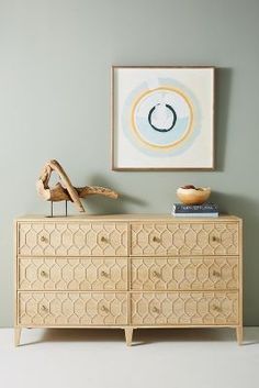 a wooden dresser sitting next to a painting on the wall