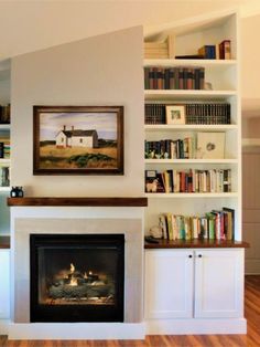 a living room with a fire place and bookshelves on the wall above it