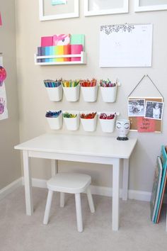 a white table topped with lots of cups filled with crayons