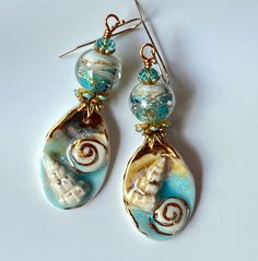 Blue long Shell earrings!  Gorgeous ceramic charms by the great artisan Annet Riabukhina paired with a beautiful artisan handmade lampwork rond bead. 22K gold lines are added by hand. The artist mark!  Swarovski faceted rondelles and gold tone and blue findings give a touch of sparkling and a rich look. All these chic and unique elements are suspended on gold filled hooks making these earrings allergy free. You're sure to attract admiration and everyone look with this fascinating unusual earrings. Very chic! Very ocean! Blue, aqua, beige, white  and gold in different textures and shapes give those earrings a special bohemian and romantic vibe.  They are about 2 3/4'' long from the top of ear wire. In all my photos, I am trying to depict colors as accurate as possible, but please be aware t Whimsical Handmade Beach Earrings, Whimsical Handmade Earrings For Beach, Artisan Turquoise Earrings For Beach, Artisan Czech Glass Jewelry For Beach, Handmade Blue Ocean-inspired Earrings, Ceramic Charms, Earrings Ceramic, Sea Jewelry, Blue Charm