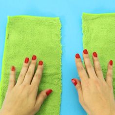 two hands with red nail polish on each hand and green towel in the other side