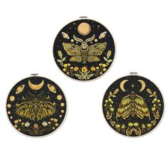 three black and gold circular wall hangings with moths, flowers and stars on them