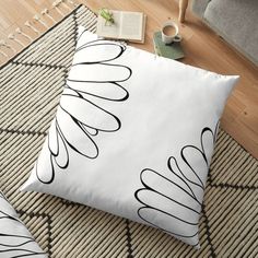 a black and white floor pillow on top of a rug next to a coffee cup