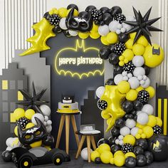 a batman themed birthday party with balloons and decorations on the wall, including a bat balloon arch