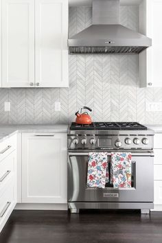 a stove top oven sitting inside of a kitchen next to white cupboards and drawers