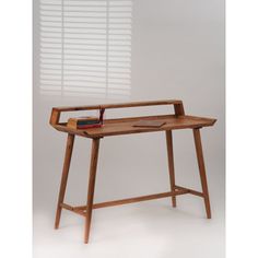 a wooden desk with a book on it and a lamp in the corner next to it