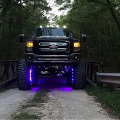 a large truck with lights on driving down a dirt road