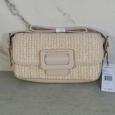 This Compact Natural Straw Shoulder Bag Features A Magnetic Snap- Buckle Style Front Closure. Complimented With Interior Pockets, Card Holder, Signature Lining And Adjustable Strap For Easy Wear. Perfect For Your Summer Resort Vacation. Material- Polyester Straw, Trim- Polyurethane Faux Leather, Lining- Polyester Small Sized Bag, 8.5" W X 4.75" H X 1.75" D Magnetic Snap Closure Strap Type- 6" - 9" Adjustable Shoulder Strap Exterior- Matte Silver Hardware Interior- Signature Logo Lining Weight- 1 Chic Sand-colored Summer Shoulder Bag, Chic Beige Shoulder Bag For Beach Season, Chic Beige Straw Bag With Detachable Strap, Chic Cream Bag For Beach Season, Chic Woven Shoulder Bag For Vacation, Chic White Straw Bag For Vacation, Spring Beach Shoulder Bag In Neutral Color, Neutral Shoulder Bag For Beach In Spring, Neutral Shoulder Bag For Spring Beach Outings