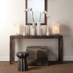 a table with candles and flowers on it in front of a mirror, stool and footstool