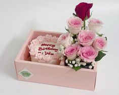 a pink birthday cake and flowers in a pink box