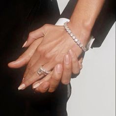 two people holding hands while wearing rings and bracelets on their wrist, with one woman's arm wrapped around the other