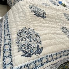 a blue and white quilted bedspread with flowers on it