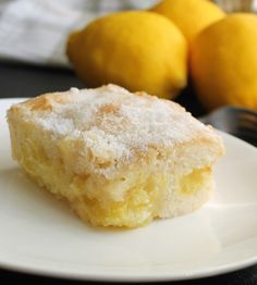 a close up of a piece of cake on a plate with lemons in the background