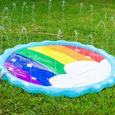 an inflatable swimming pool with a rainbow painted on the side and water sprinkles all around it