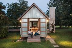 two people sitting on the porch of a tiny house