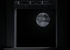 a full moon seen through a window in the dark