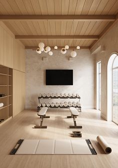 an empty room with yoga mats on the floor and a flat screen tv above it