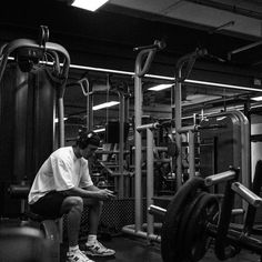 a man sitting on top of a bench next to a barbell in a gym