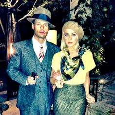 the man and woman are dressed up for an outdoor event, posing for a photo