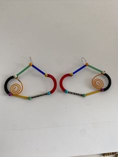 two pairs of colorful bracelets hanging from hooks on a white wall in a room