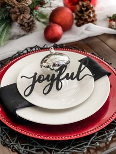 a christmas table setting with red and white plates, black napkins and silverware