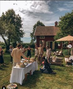 a group of people standing around a table with food on it in front of a house