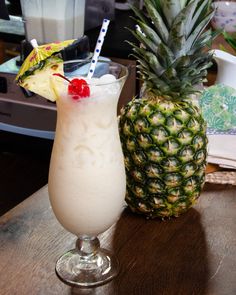 a pineapple drink in a tall glass with a straw