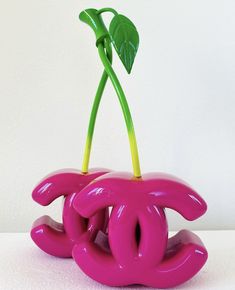 a pink sculpture with a green plant in it's center on a white surface