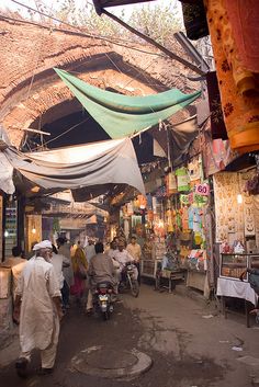 several people are walking through an open market