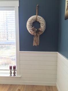 a wreath hanging on the wall in a room with blue walls and wood flooring