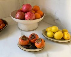 three bowls filled with fruit sitting on top of a counter next to other fruits and vegetables