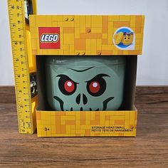 a lego mug with red eyes and a skull head in a box on a table