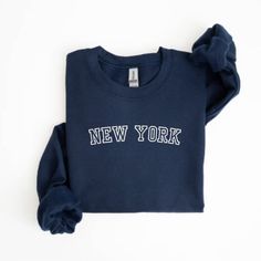 Get ready to fall in LOVE with your new embroidered New York sweatshirt. It's the cutest and most comfortable way to show off the latest styles. Also would be a great gift! * PRODUCT DETAILS * ✺ Soft preshrunk 50% cotton, 50% polyester blend ✺ Medium weight fabric (super soft feel) ✺ Wash and dry normally (on cool for best results) ✺ Designed and printed in the USA ✺ Due to different monitor screens, colors may vary ✺ * SIZING * ✺ FOR AN OVERSIZED FIT, SELECT TWO OR THREE SIZES UP FROM YOUR NORM Navy Varsity Long Sleeve Sweatshirt, Varsity Long Sleeve Top With Letter Embroidery, Navy Letter Print Sweatshirt For Fall, Long Sleeve Sweatshirt With School Spirit Embroidery, Fall Fleece Tops With Letter Embroidery, Collegiate Style Fall Sweatshirt With Embroidered Text, Collegiate Embroidered Text Sweatshirt For Fall, School Spirit Long Sleeve Embroidered Sweatshirt, Collegiate Style Embroidered Sweatshirt For Fall