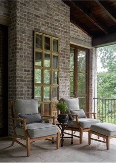 two chairs sitting on top of a patio next to an open door with windows above them