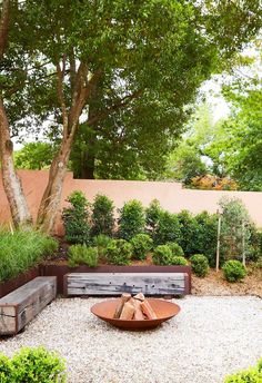 a wooden bench sitting in the middle of a garden next to trees and shrubbery