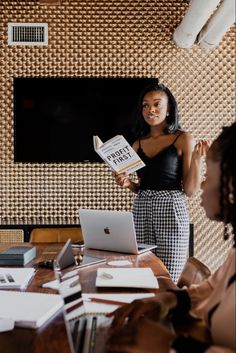 a woman standing in front of a laptop computer while holding up a book with the title, how to write better fiction