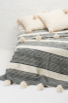 a black and white striped bed with pom - poms on the pillowcase