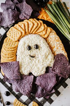 a plate with crackers, chips and cheese in the shape of a ghost