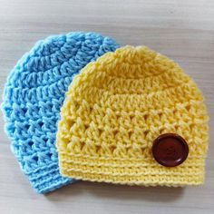 two crocheted hats sitting on top of a wooden table next to each other