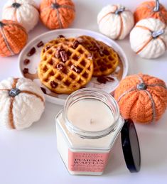 pumpkins and waffles are sitting on a plate next to a candle