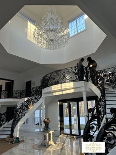 an elegant staircase with chandelier and marble flooring in a large white house